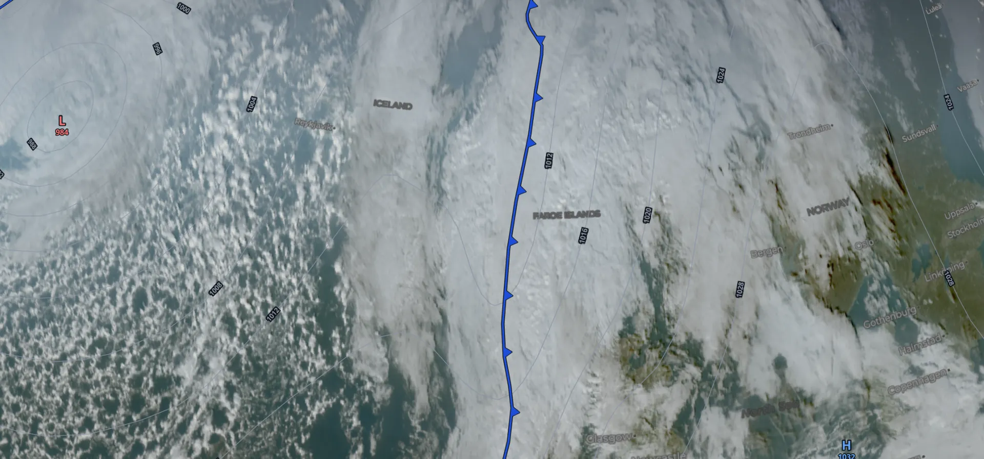 The SkyNexus enroute map with the Fronts, Isobars and Satellite layers on. A blue cold front line with triangles runs south past the Faroe Islands along a long band of cloud, with a low near Greenland on the left and a field of small shower cells in the cold air behind the front.